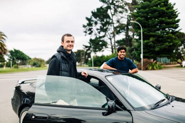 Two men standing next to a car