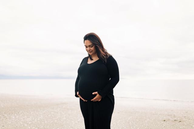 A pregnant woman looks at and holds her belly