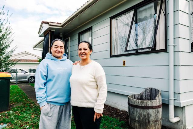 two women standing in front of a house