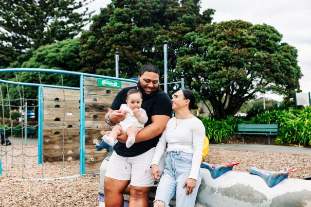 A couple with their infant child at a playground