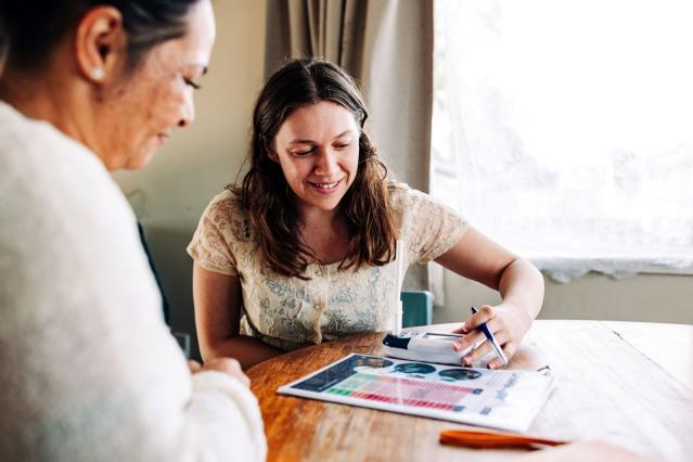 A person helping someone with a plan written down on paper