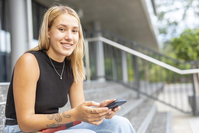 a woman with a phone sitting on steps outside a building