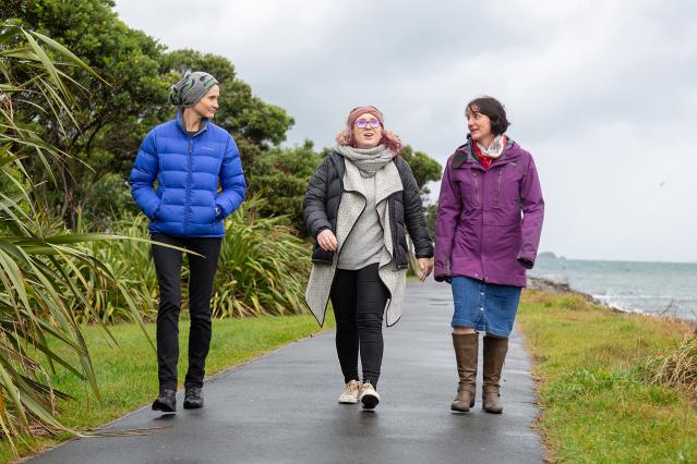 Three people walking down an outdoor path